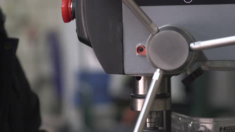 hand moving down pilot feed lever of a drill press machine - close up