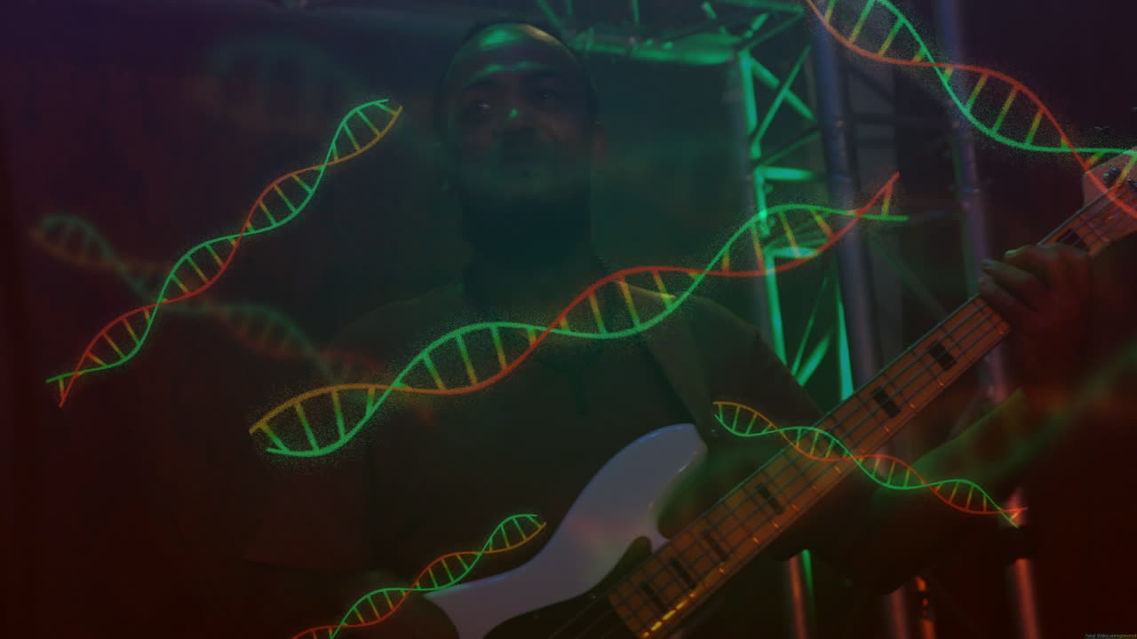 Male musician playing white bass guitar for live music show, showing red green DNA helix graphics