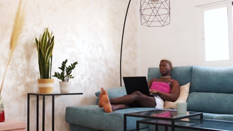 person using a laptop while relaxing on a couch in a living room
