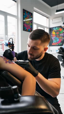 A professional tattoo artist applying a tattoo on a client&#039;s arm in a modern studio