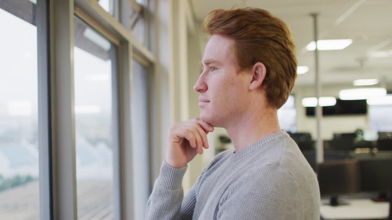 Profilo di un uomo d'affari creativo caucasico pensieroso che si tocca il viso e guarda attraverso la finestra