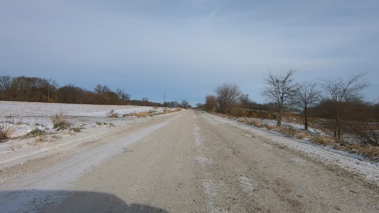 Point of View out of the drivers window; Driving past farms, cows, truck and fields in rural Illinois USA on snow and ice.