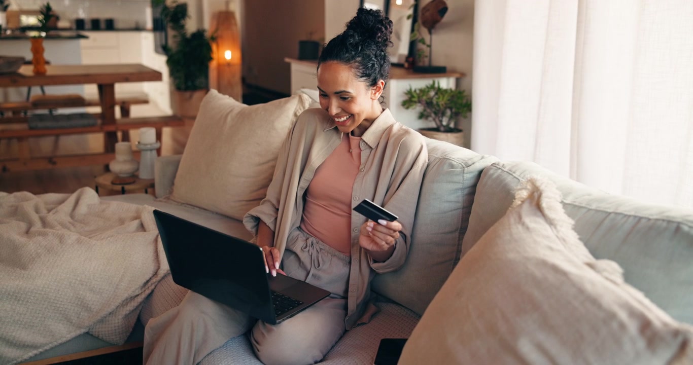 Giovane donna che fa shopping online con carta di credito sul laptop a casa