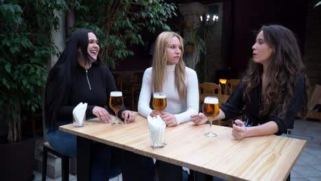 mejores amigas felices riendo y bebiendo cerveza en el bar