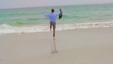 rear view of caucasian businessman running with blazer on the beach 4k