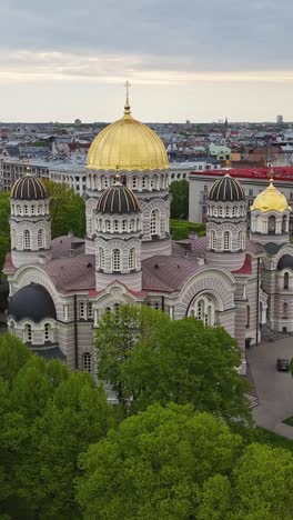 golden dome of riga cathedral and lush green trees on the vertical esplanade