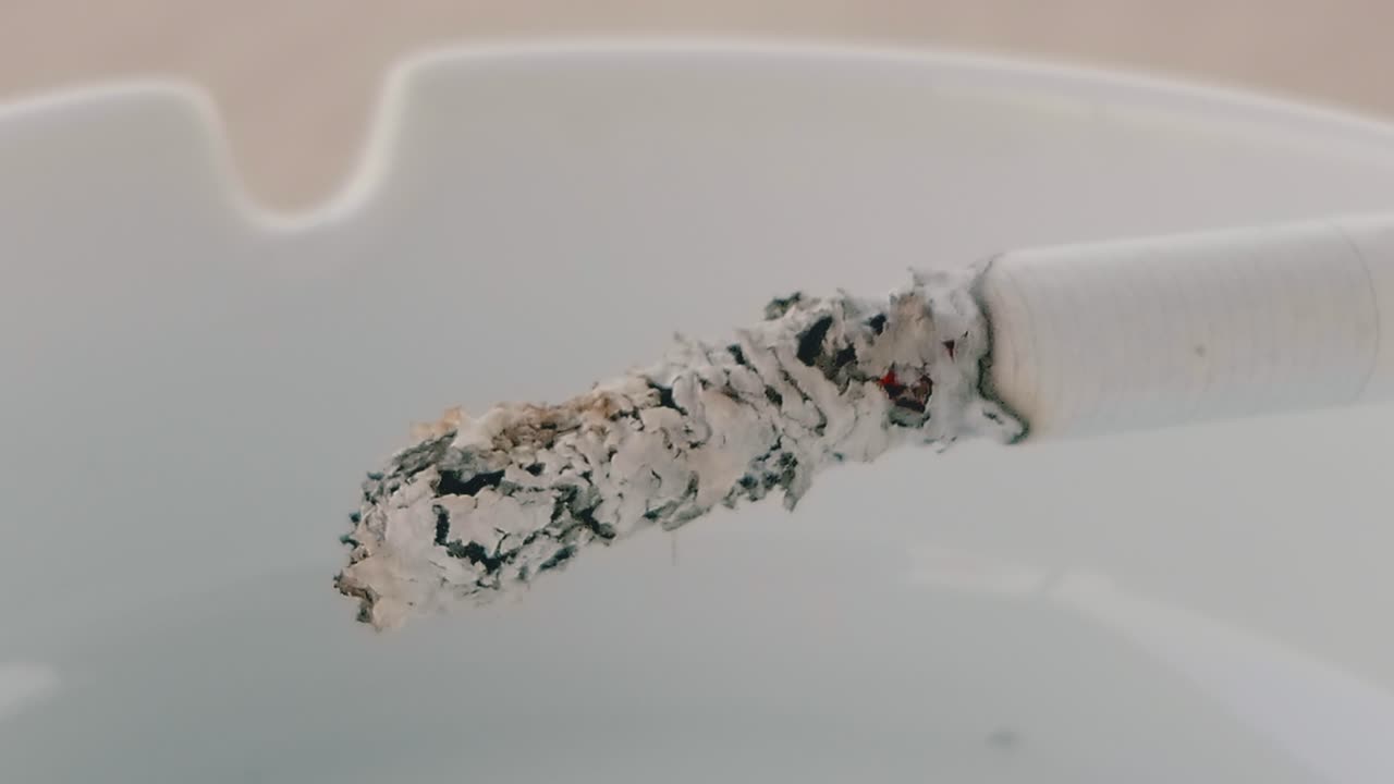 재가 끝에서 떨어지기 전에 재떨이에서 타는 담배의 타임랩스 샷