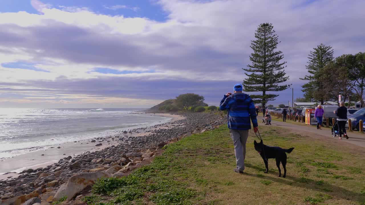Man With His Pet Dog On Leash Walking At The Crescent Head Beach - Morning Walk Along The Sea Coast - New South Wales, Australia - wide shot