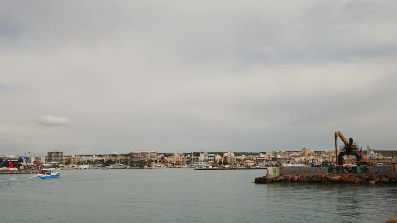 Traghetto taxi acqueo in arrivo al porto di Santa Pola dall'Isola di Tabarca sotto un cielo nuvoloso e drammatico ad Alicante, Spagna.