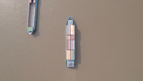 topdown view of a logistic transport container ship on the river with another boat passing by