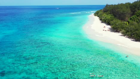 a tropical island paradise with tourists swimming in shores of the clear blue waters with perfect weather