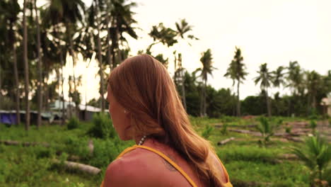 a beautiful blonde caucasian girl is riding on a skateboard between the palm trees - close-up slow-motion shot