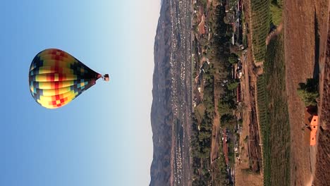 Hot-air-balloon-floating-over-the-Temecula,-California-wine-country-landscape---vertical-orientation-from-an-aerial-perspective