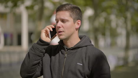 smiling young man talking by cell phone outdoor