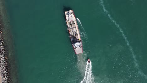 Una-Gran-Draga-Industrial-Maniobra-En-El-Agua-Mientras-Un-Buque-Piloto-Rápido-Navega-Al-Lado-Del-Barco