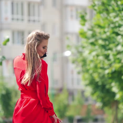 incredible woman in the city. portrait of a beautiful young female who is talking on a mobile phone. gorgeous smiling lady in red dress outdoors in summer.