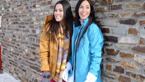 laughing twins in jackets and glove near wall