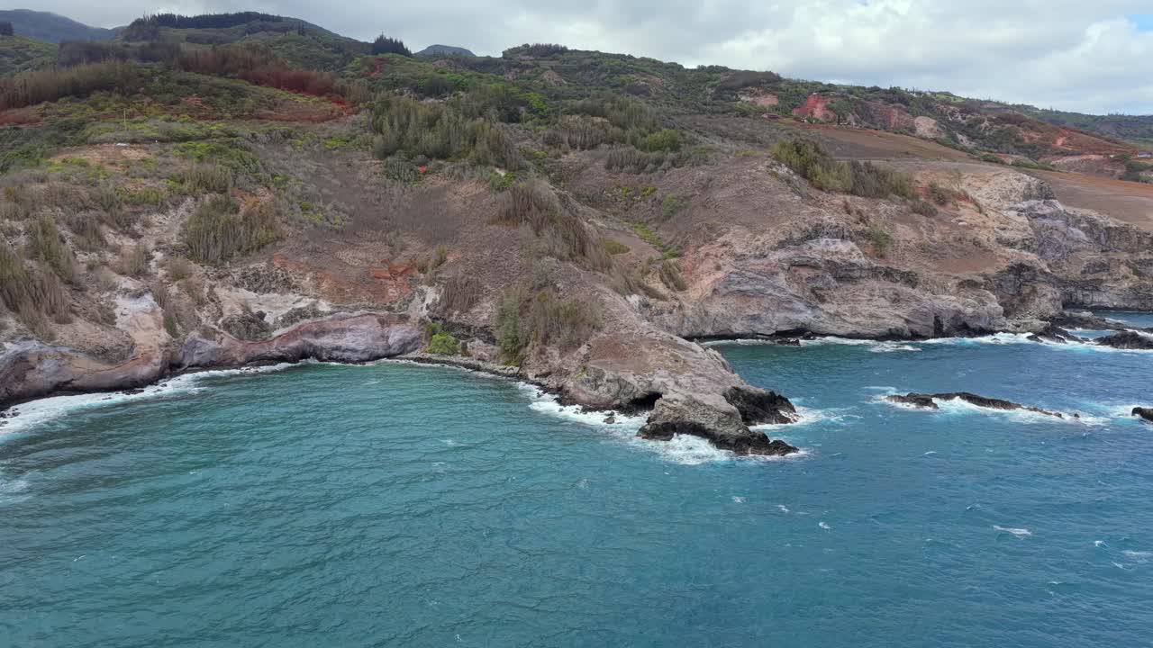 Drone pans across a rocky Hawaiian shore rarely seen by visitors, revealing epic cliff faces and turning to show the magnificent view of the island from the sea. 3 of sequence of 5