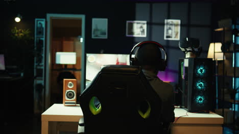 hombre jugando a un videojuego espacial en una pantalla de pc en una habitación oscura.