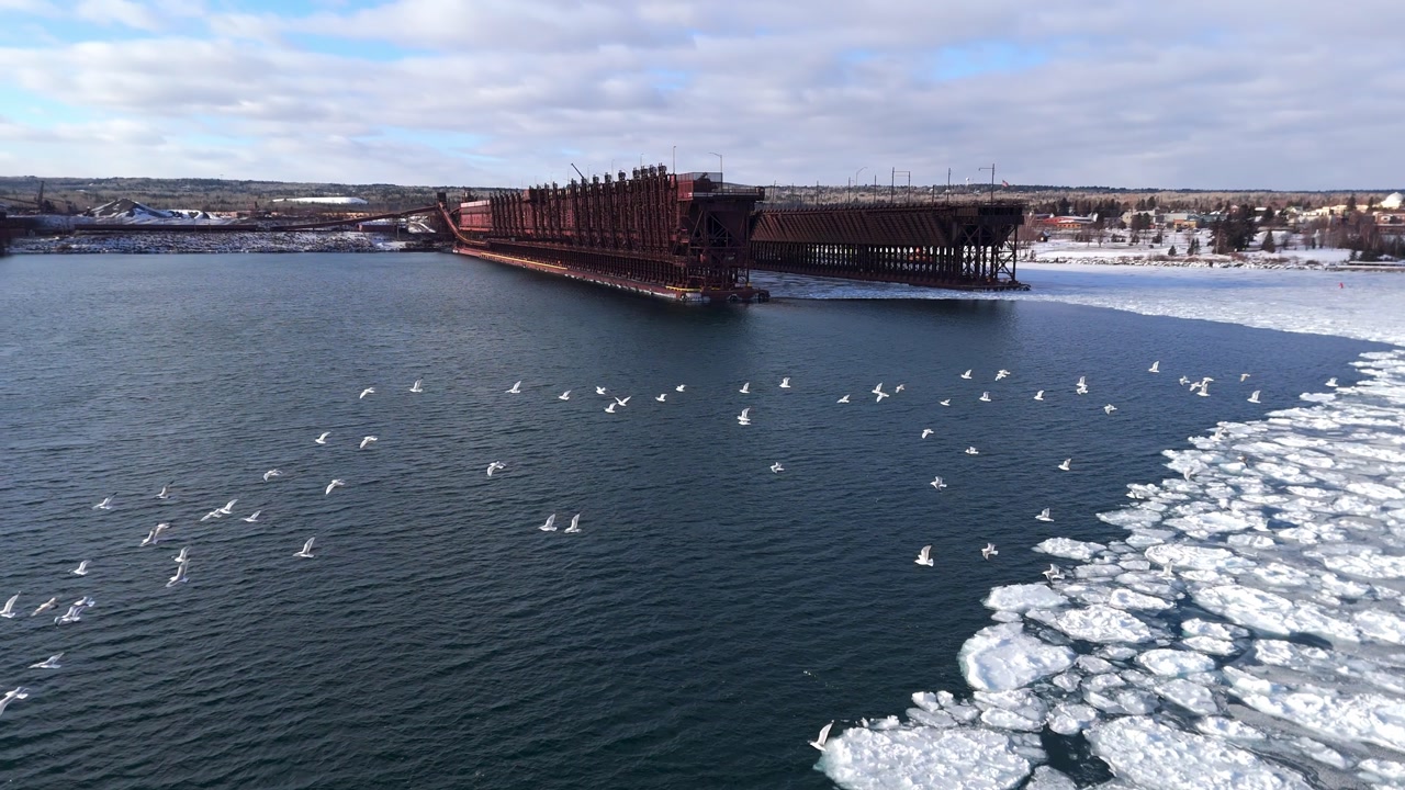 Flock of seagull flying over Lake Superior on a winter sunset with ice formations on lake surface, Two Harbors Minnesota