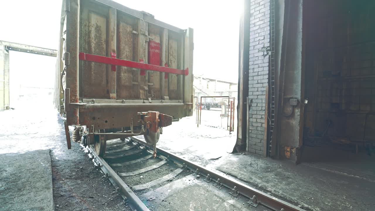 Old and rusty container leaves on the rails from the tunnel on the territory of the railway. Close-up. View of bottom.