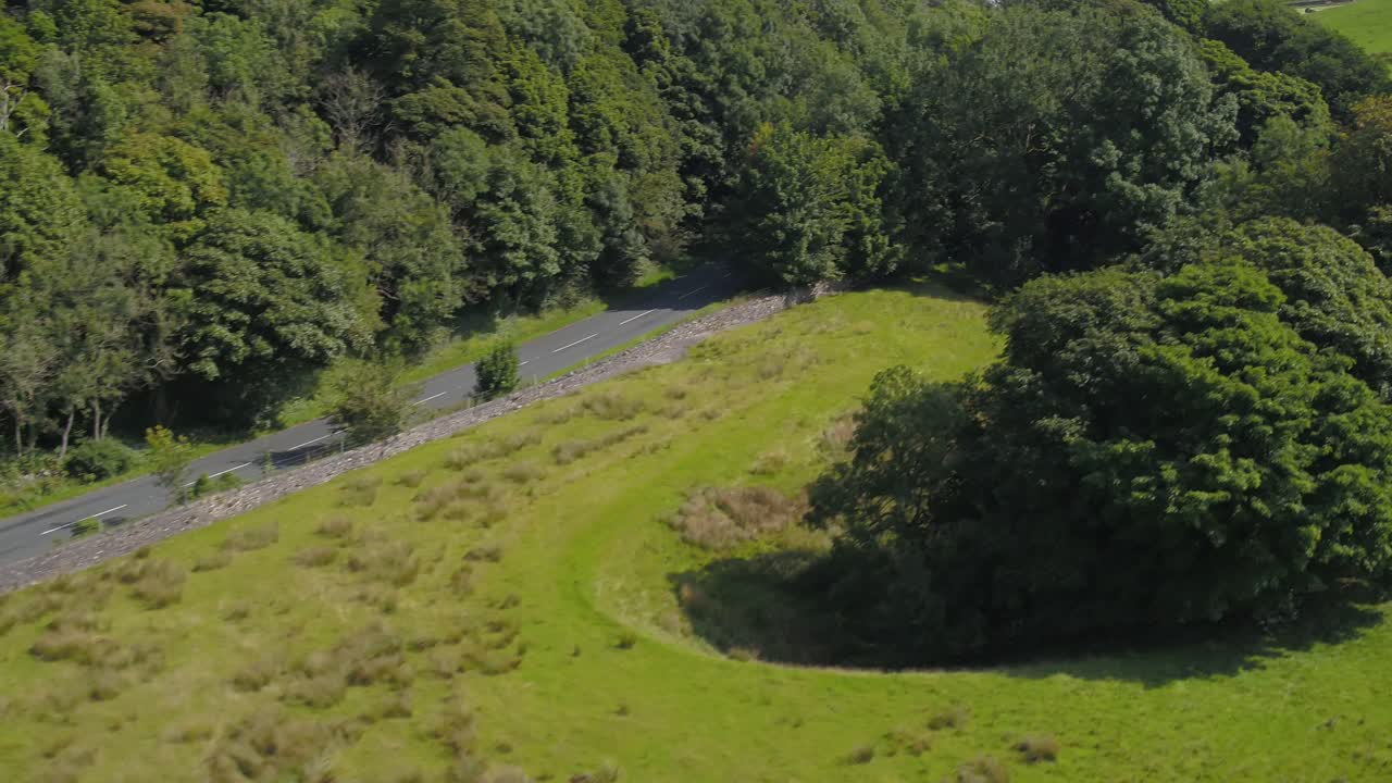 hermoso movimiento de avión no tripulado desde la parte inferior de un árbol cubierto de peñasco de piedra caliza, ascendiendo y panoramizando revelando valles, colinas, tierras de cultivo, campos, paredes de piedra seca y el paisaje rural de yorkshire