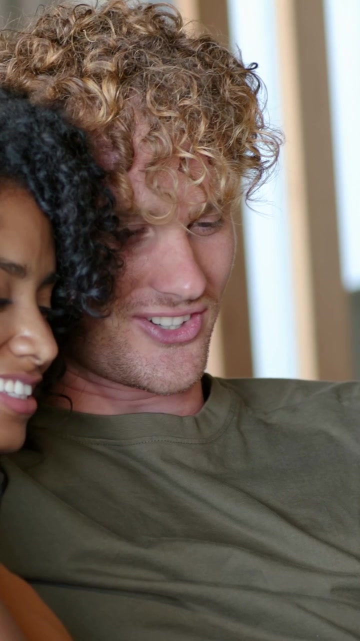 Man shifting and smiling as woman entering and leaning, bonding on couch by slats for marketing