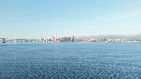 a slow zoom out view of the san francisco bay bridge and embarcadero in the distance.