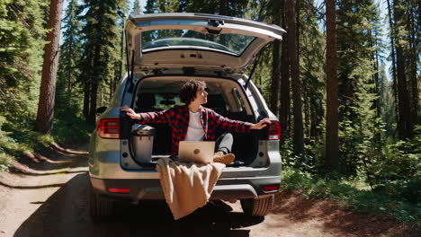 suv parked in the forest with person working on laptop