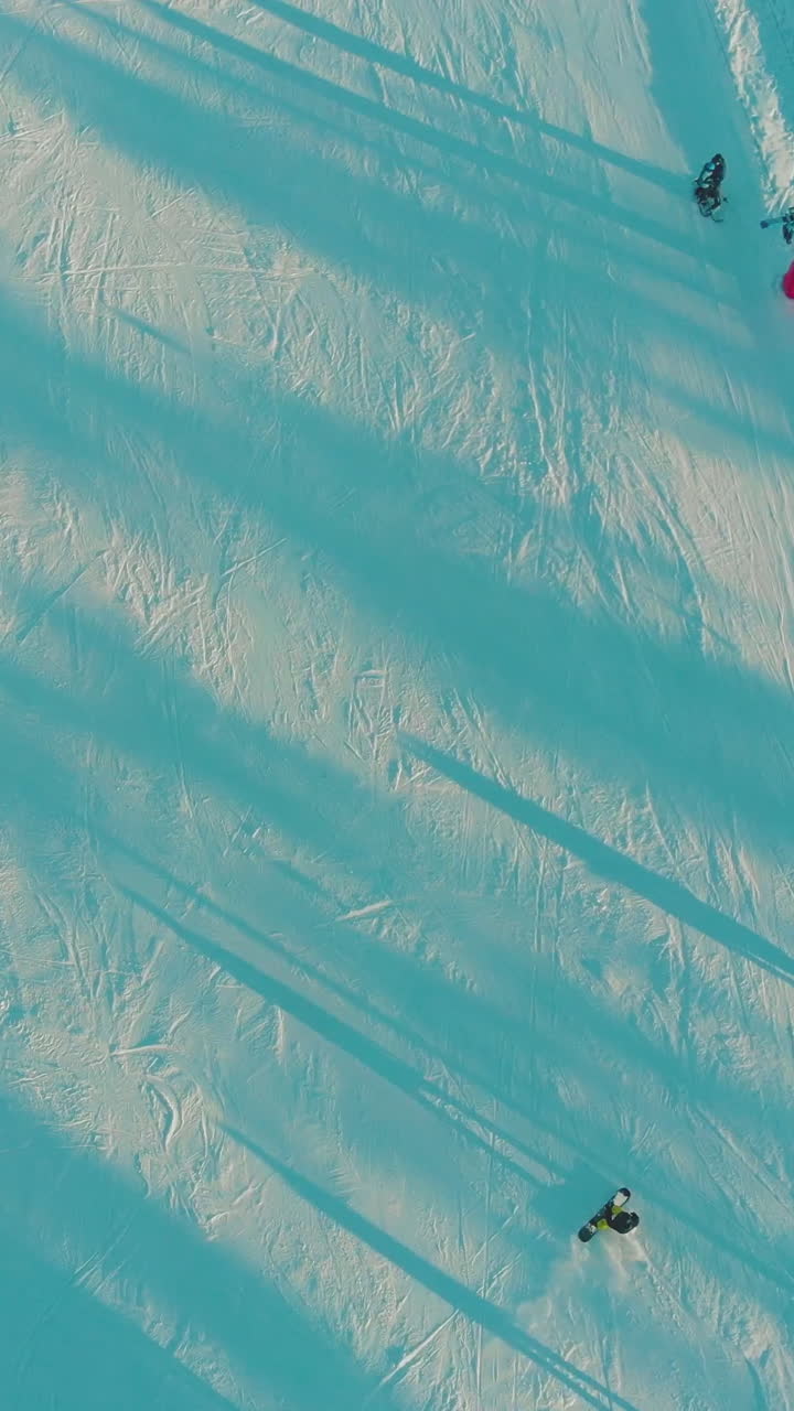 beautiful wide snowy ski track with people skiing in shady and sunny places at comfortable resort on frosty day aerial