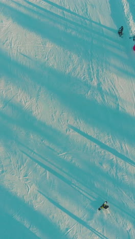 beautiful wide snowy ski track with people skiing in shady and sunny places at comfortable resort on frosty day aerial