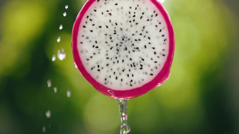 Agua-Que-Fluye-Por-Una-Rodaja-De-Fruta-De-Dragón-Fresca-Con-Goteo-Líquido-En-Cámara-Lenta-Fondo-Retroiluminado-Brillante