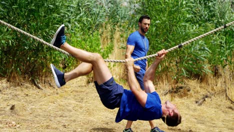 hombre cruzando la cuerda durante el curso de obstáculos 4k