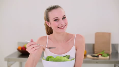 modelo sonriente comiendo un gran plato de ensalada