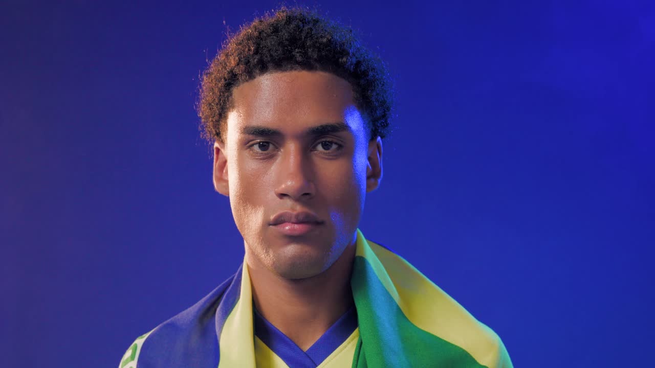 Uomo afroamericano che inclina la testa, bandiera giallo-verde che gli scivola sulle spalle in studio mostrando supporto