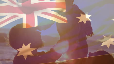 animation of australian flag over happy caucasian parents holding up baby on sunny beach