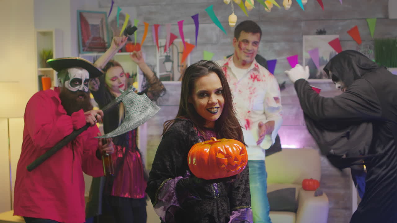 마녀처럼 옷을 입은 아름다운 여성이 호박으로 주문을 하고 있습니다.