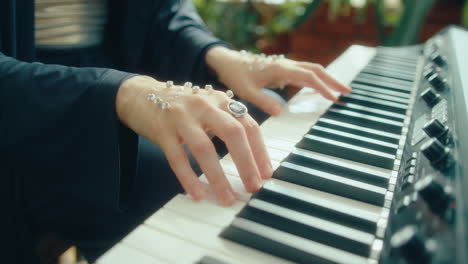 hands of female pianist embellished with crystals playing keyboard