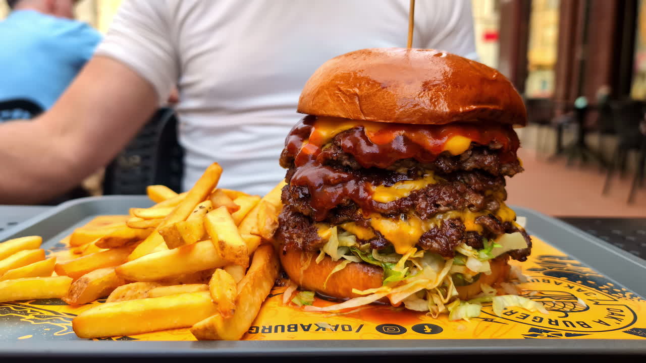 Hamburger with fries and soft drink served on rustic outdoor table