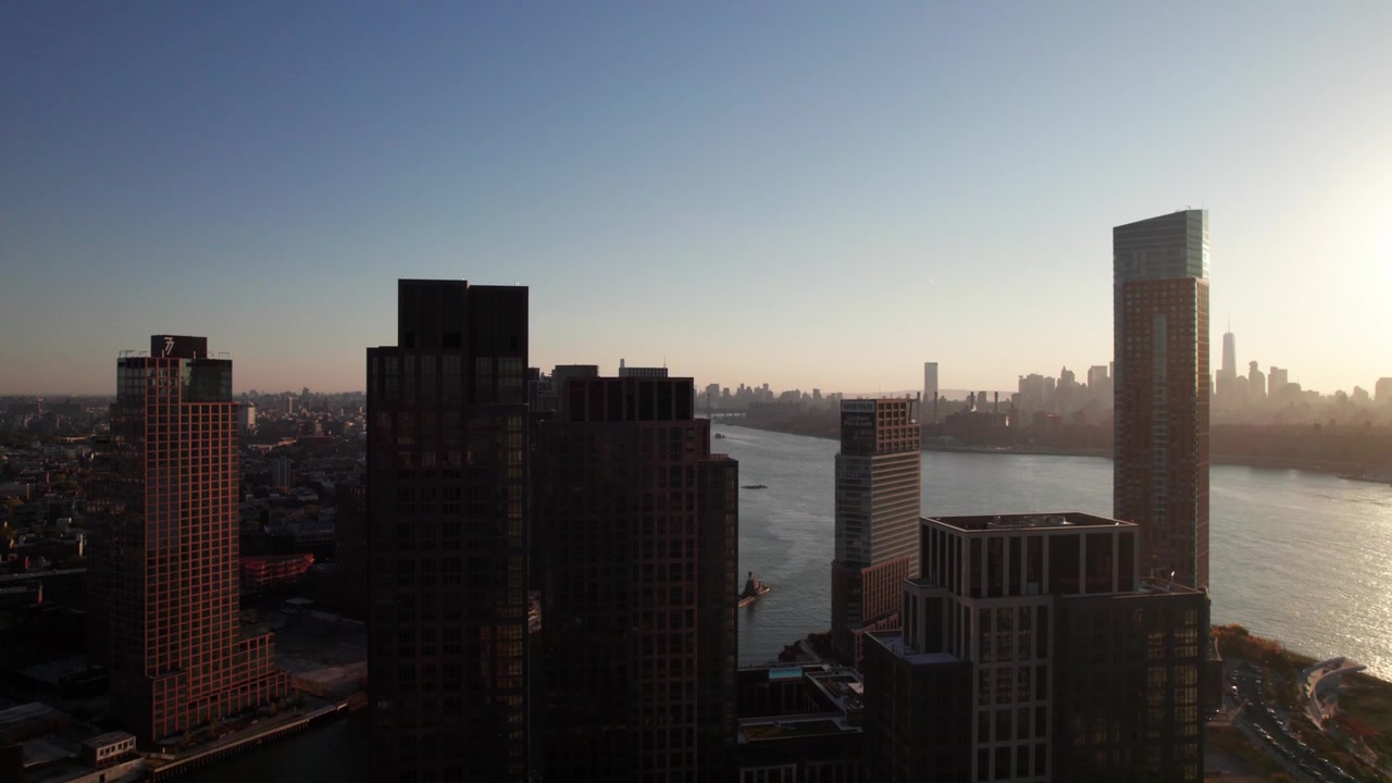 Condominios de gran altura en Long Island City, el East River y el horizonte de Manhattan de fondo. Toma aérea ascendente, 4K.