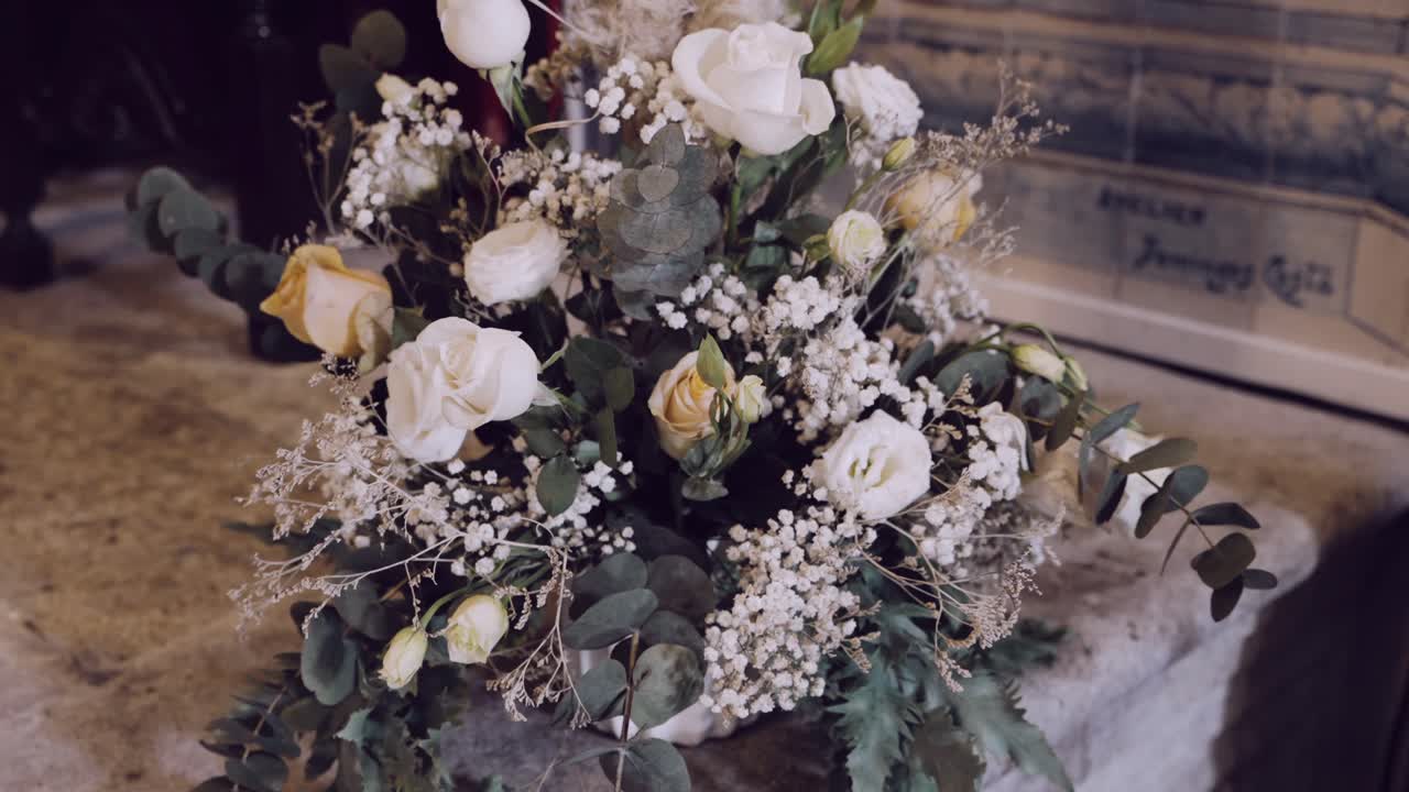 Nærbillede af et sart blomsterarrangement med hvide og cremefarvede roser på en stenoverflade