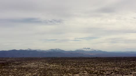 Aerial-tilt-down-from-the-snow-capped-mountains-of-the-Mazatzals-to-the-desert-Sonoran-Desert,-Scottsdale,-Arizona
