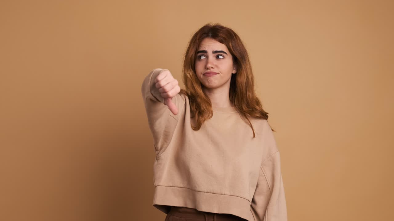 Young woman gesturing disagreement with thumb down