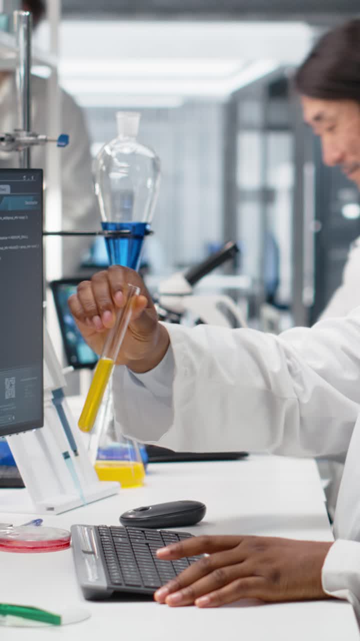 Vertical video Lab scientist evaluates genetic markers using PC, analyzing sample properties
