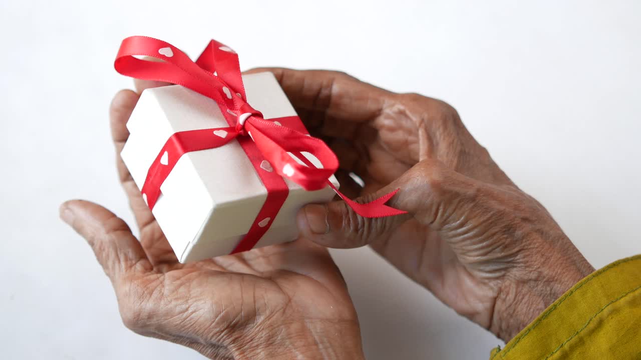 manos de ancianos sosteniendo una caja de regalos