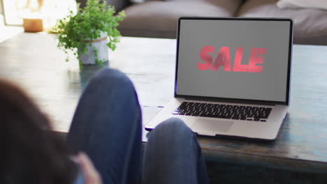 Knees-of-woman-at-table-using-laptop,-online-shopping-during-sale,-slow-motion