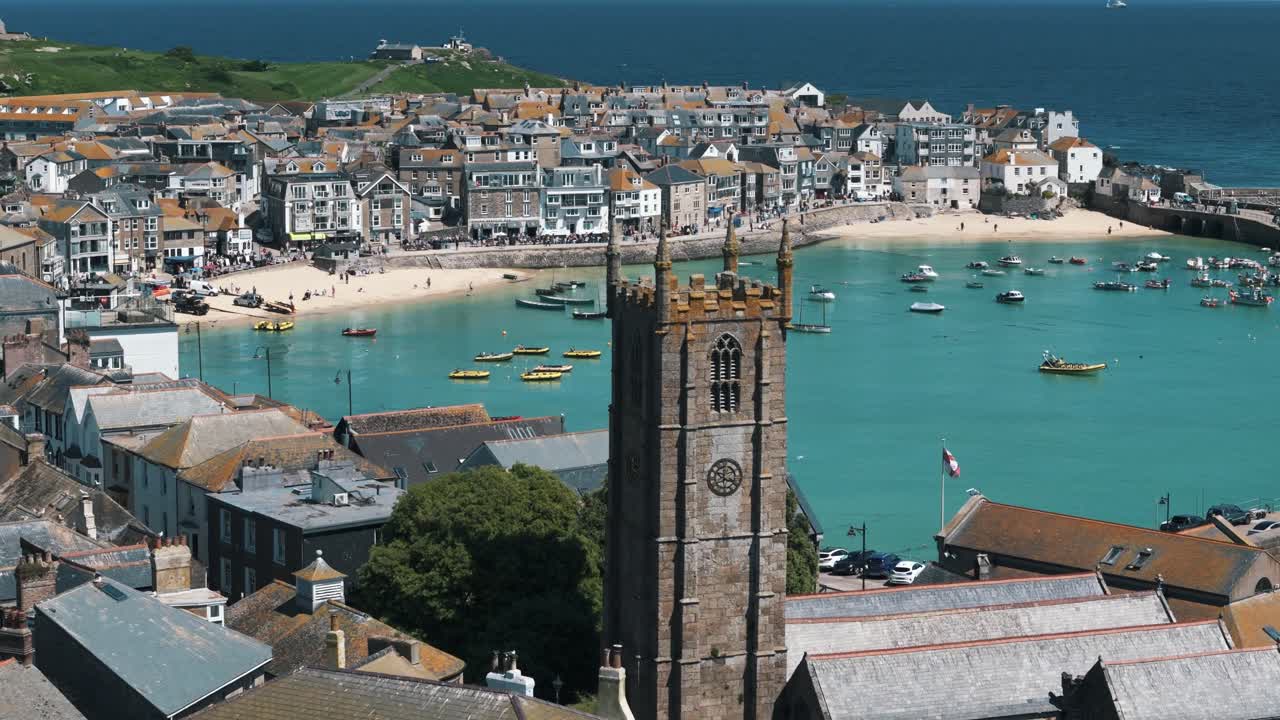 Right establishing aerial orbit around Saint Ives church revealing coastal town and blue sea