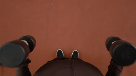 overhead view of a person holding dumbbells during a workout