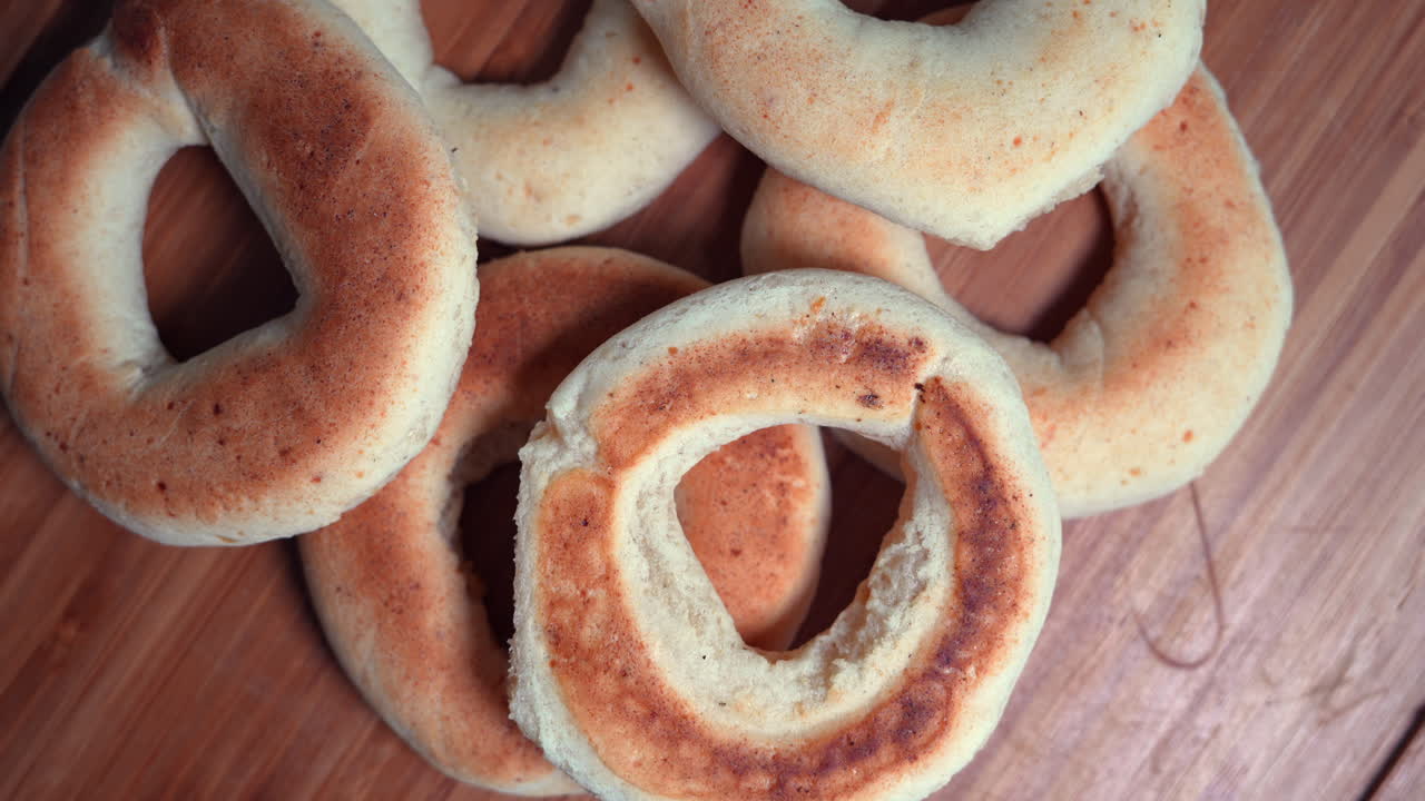 A tantalizing close-up shot of freshly baked pandebonos, showcasing golden textures and rustic charm on a wooden table. The lighting enhances the delightful warmth and inviting appeal