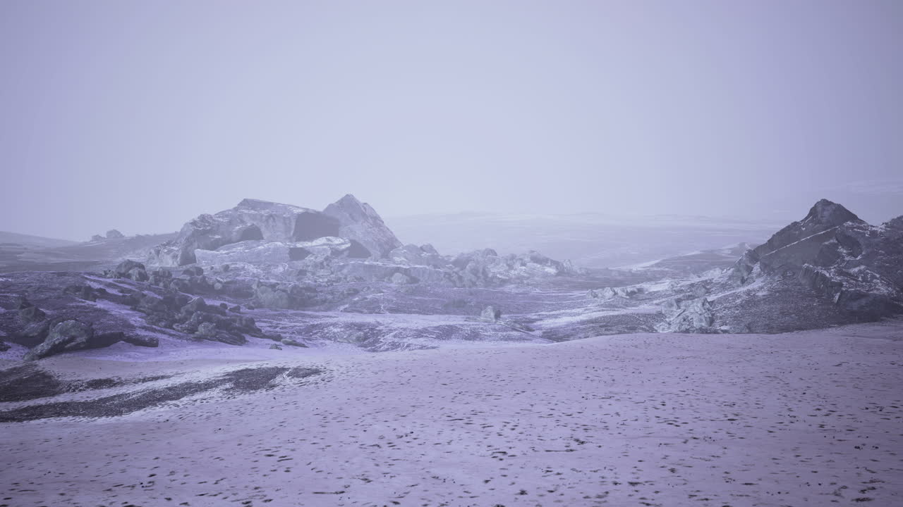 Frozen landscape at twilight with rugged rocks and gentle snow cover